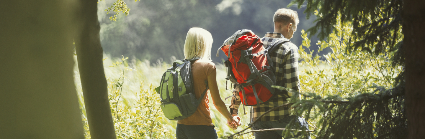 http://Couple%20With%20Backpacks%20Holding%20Hands%20Hiking%20In%20Sunny%20Woods