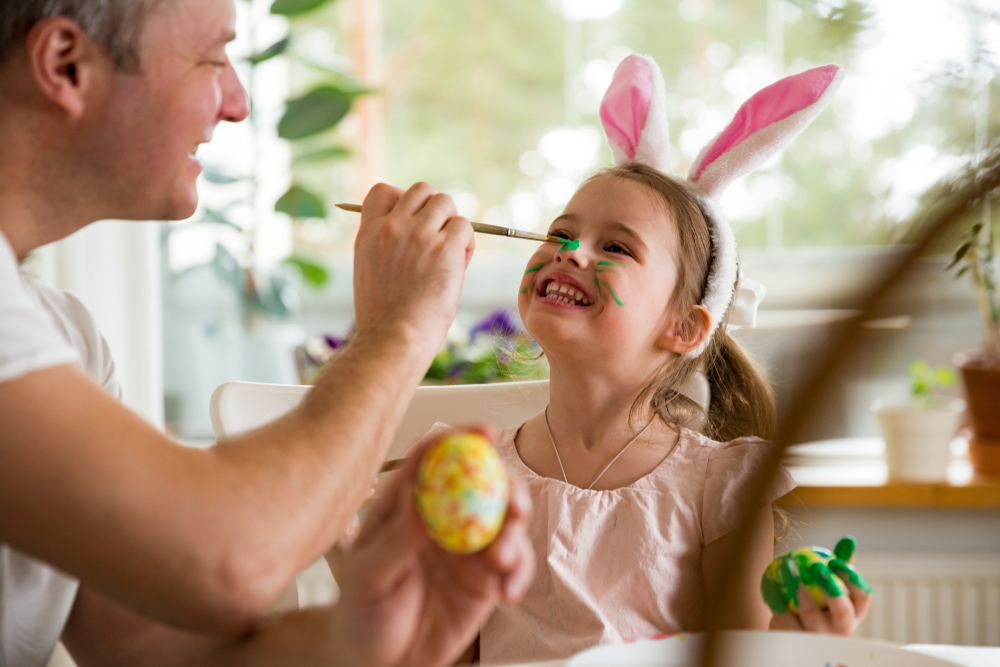 A,father,and,daughter,celebrating,easter,,painting,eggs,with,brush.